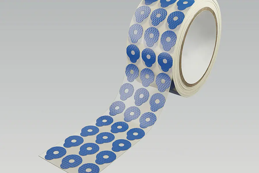 Rolle mit blauen Formstanzteilen und Innenausschnitten auf Trägerbahn